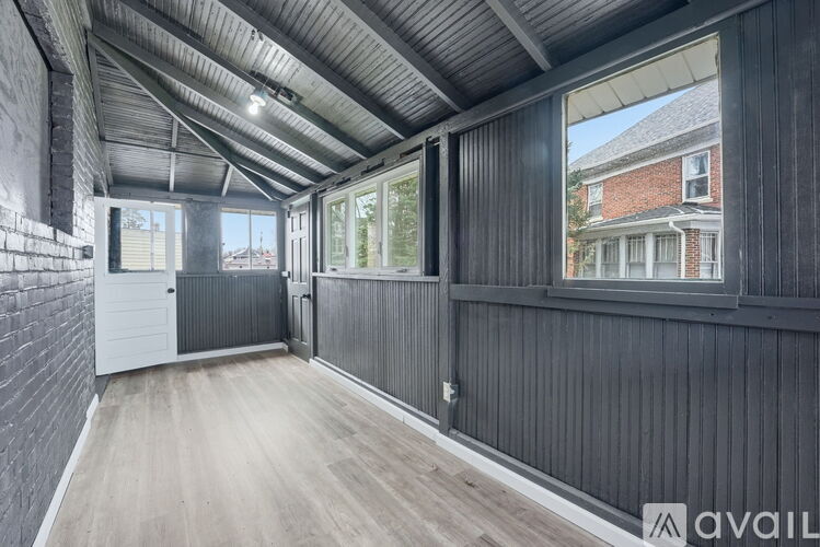 A room with a grey wall and wooden floor is available for rent.