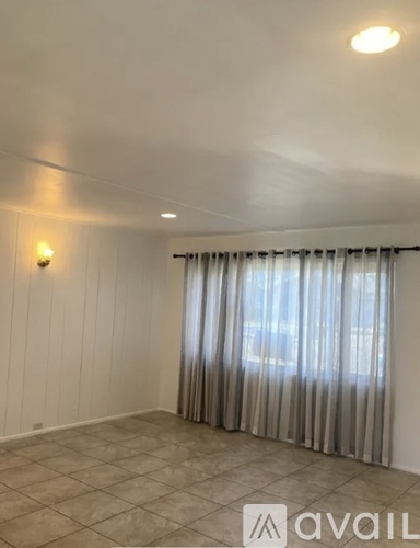 A room with a window covered by curtains and a wall-mounted light fixture.