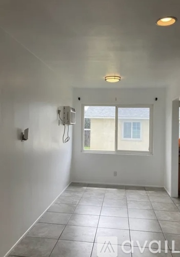 A white bathroom with a window and a shower head.