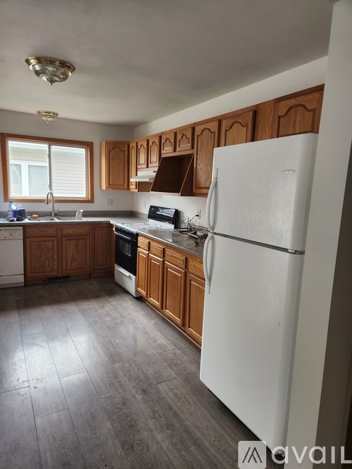 A kitchen with a white fridge, wooden cabinets, and a tiled floor.