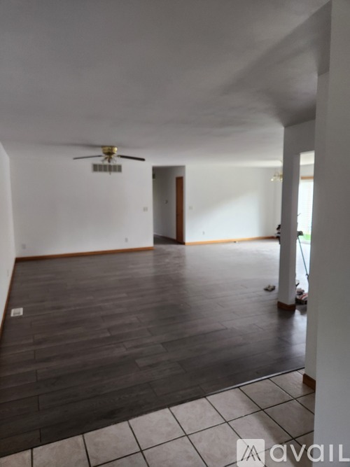 A room with a ceiling fan and wooden flooring.