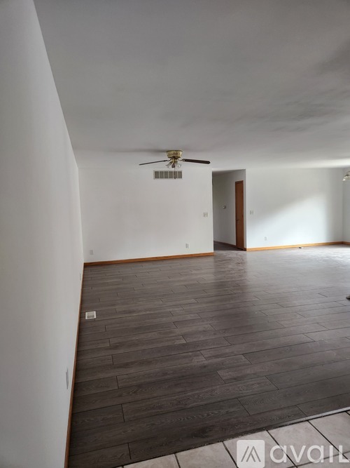 A room with a ceiling fan and wooden flooring.