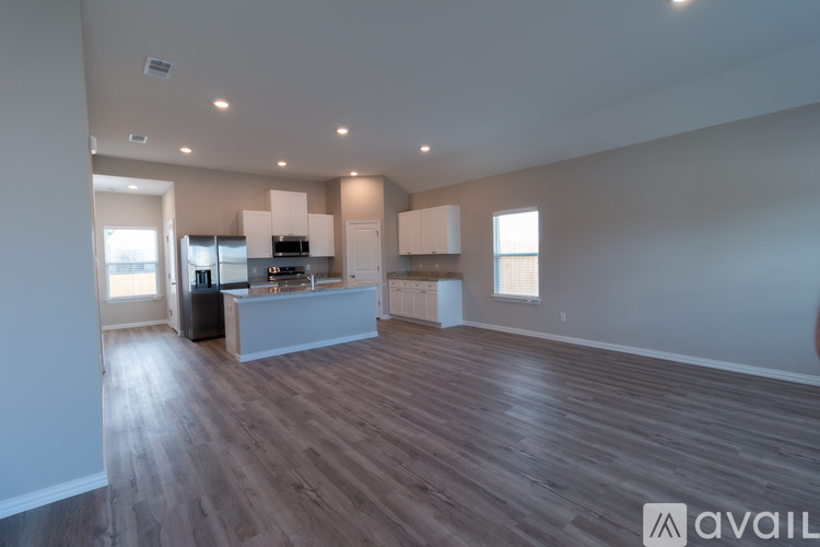 A spacious kitchen with white cabinets and a wooden floor.