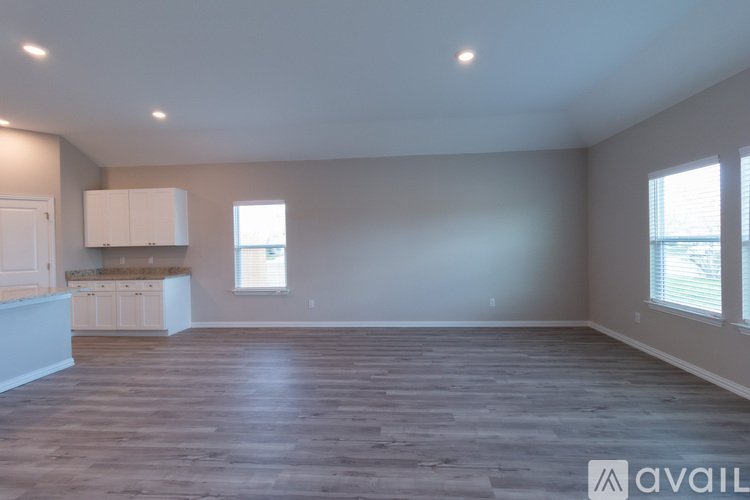A spacious room with wooden flooring and a window.