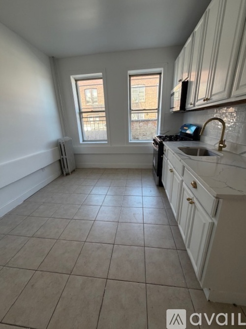 A kitchen with white cabinets and a tiled floor.