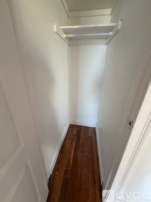 A narrow hallway with wooden floors and white walls.
