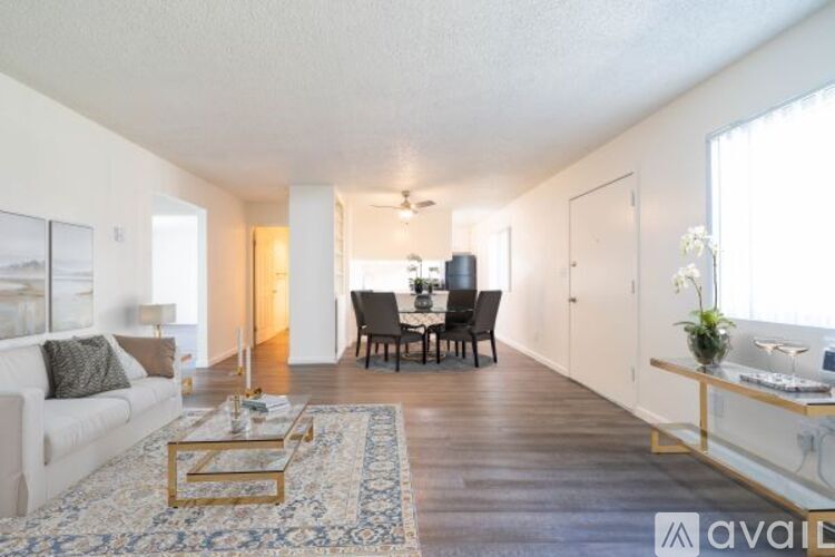 A living room with a white couch, a coffee table, and a dining table with chairs.