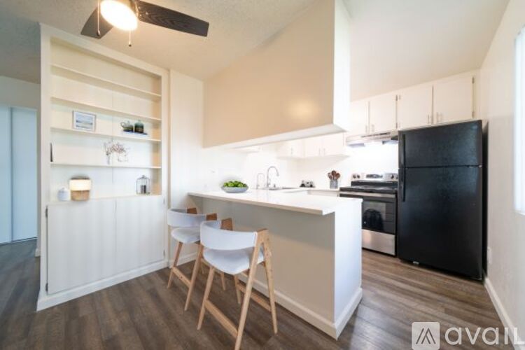 A kitchen with a black refrigerator and white countertops.