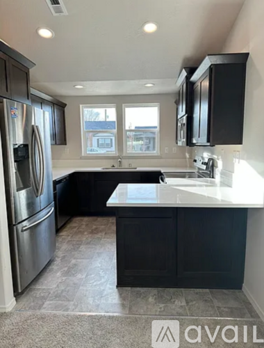 A kitchen with black cabinets and a stainless steel refrigerator.