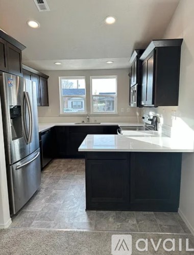 A kitchen with black cabinets and a stainless steel refrigerator.