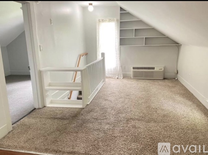 A room with a carpeted floor and a staircase leading to another room.