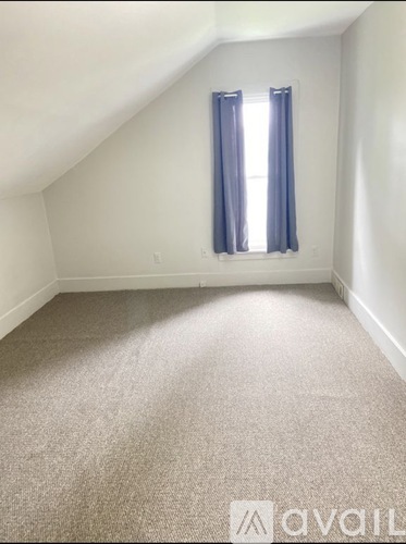 A room with a carpeted floor and a window with blue curtains.