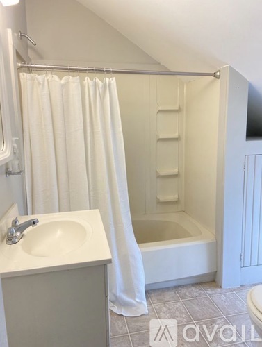 A bathroom with a white shower curtain and a white sink.