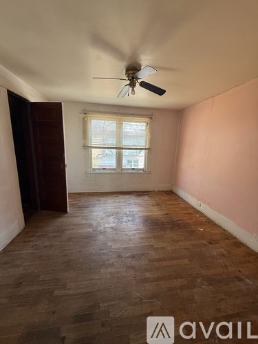 A room with wooden flooring and a ceiling fan.