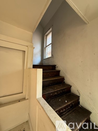 A staircase with a white railing and a window above it.