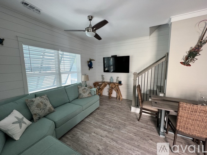 A living room with a green couch, a wooden table, and a television mounted on the wall.
