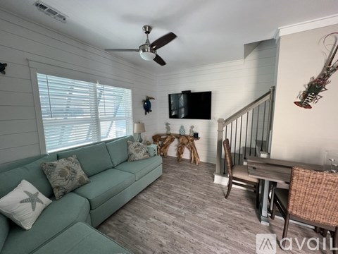 A living room with a green couch, a wooden table, and a television mounted on the wall.