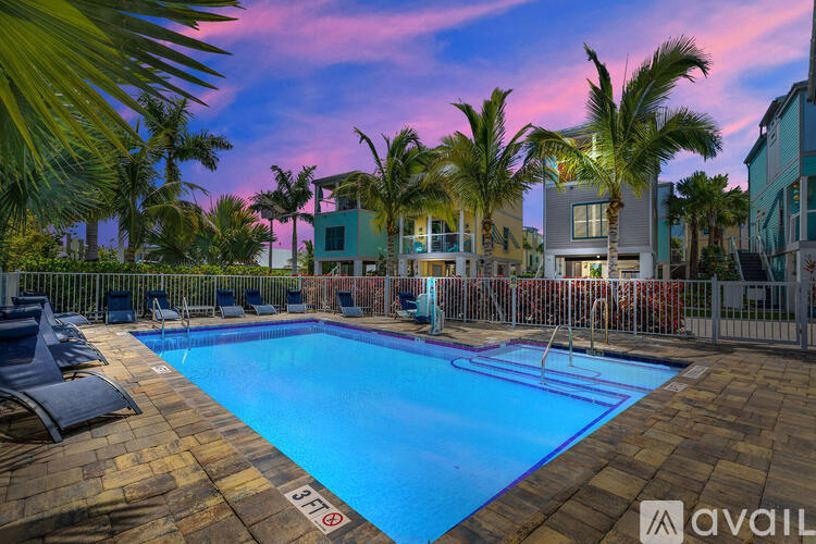 A pool surrounded by palm trees and chairs.