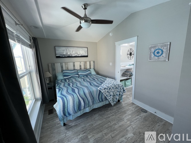 A bedroom with a bed, a ceiling fan, and a window with curtains.