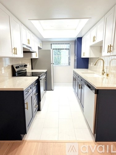 A kitchen with black and white cabinets and a wooden floor.