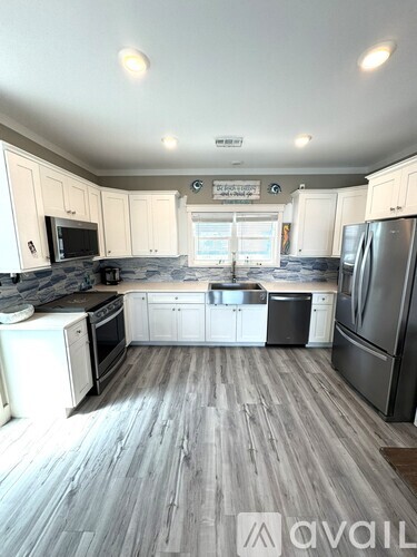 A kitchen with white cabinets and a wooden floor.