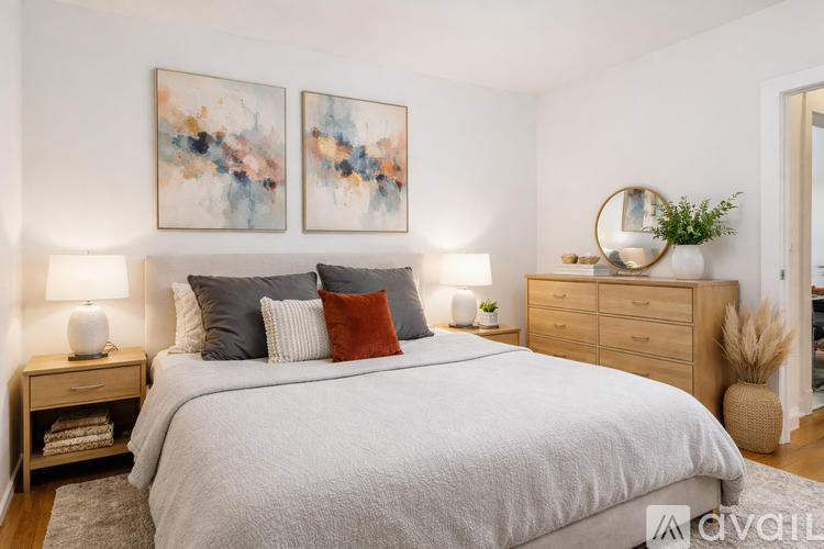 A bedroom with a large bed, two nightstands, and a painting on the wall.