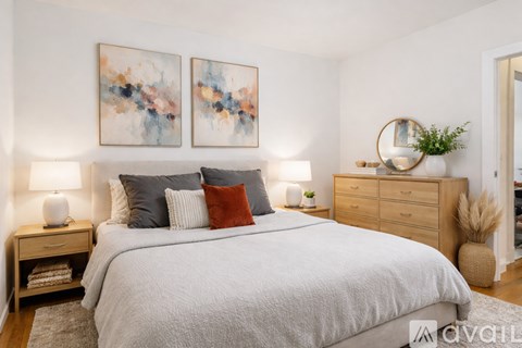 A bedroom with a large bed, two nightstands, and a painting on the wall.