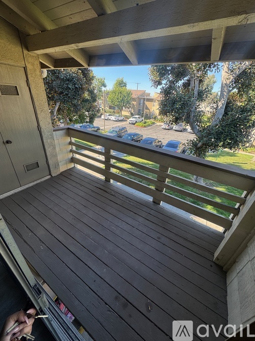 A balcony with a view of a parking lot and trees.