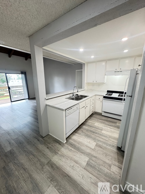 A modern kitchen with white cabinets and a wooden floor.