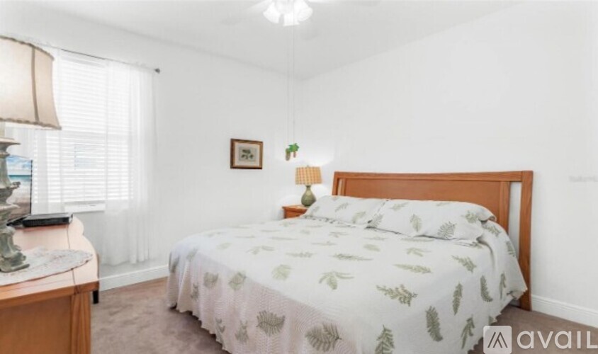 A bedroom with a bed, nightstand, and lamp.