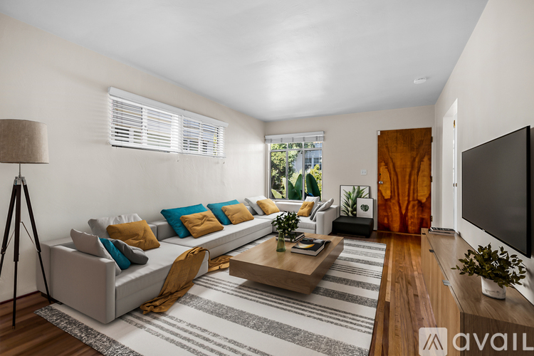 A living room with a grey sofa, a wooden coffee table, and a television on the right side.