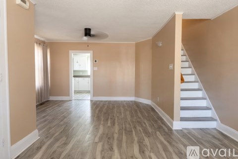 A room with wooden flooring and a staircase on the right side.
