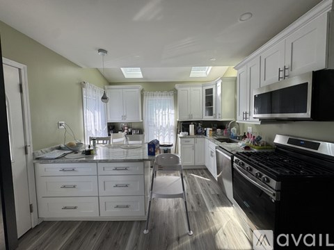 A kitchen with white cabinets and a black stove top oven.