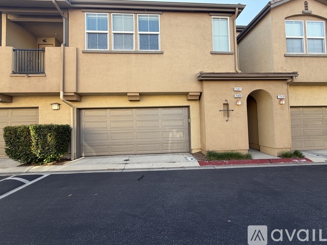 A beige house with a garage door and a balcony.