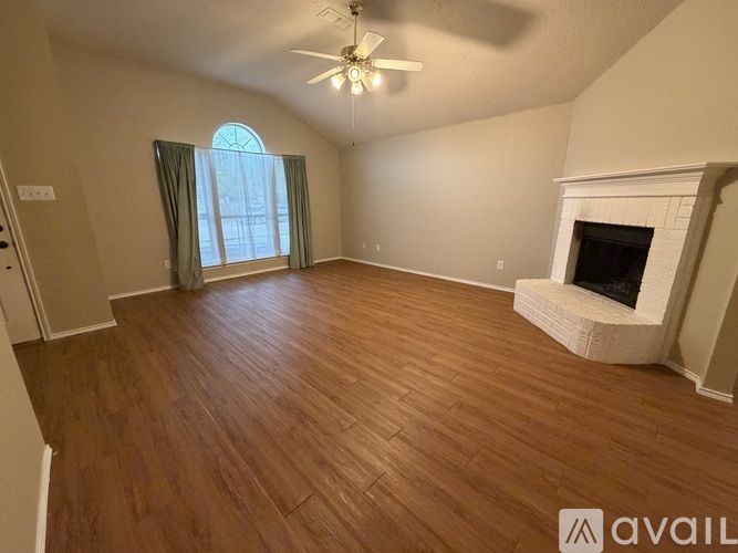A spacious room with wood flooring and a fireplace.