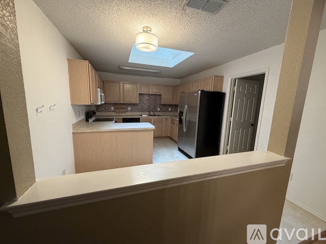 A kitchen with a black refrigerator and wooden cabinets.