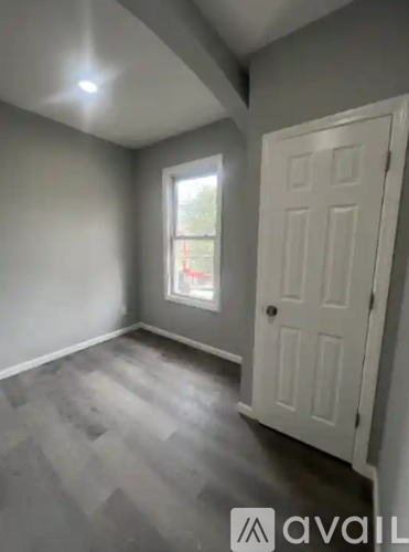 A room with a white door and a window with a red curtain.