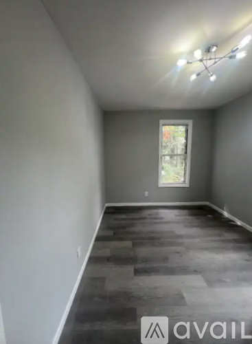 A room with a window and a wooden floor.