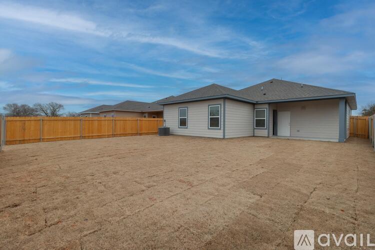 A house with a brown fence and a grey roof is available for rent.
