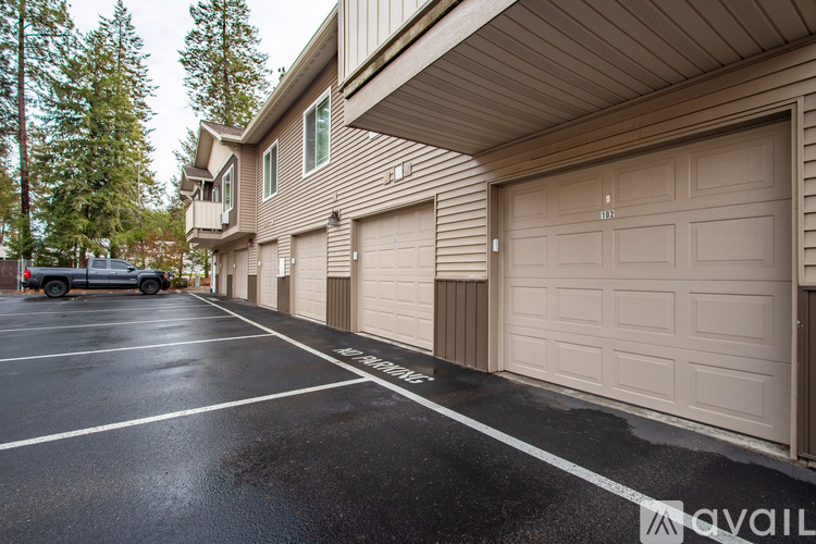 A parking lot with a car parked and a building with garage doors.