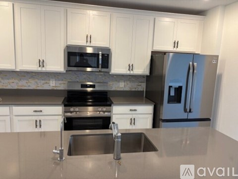 A kitchen with a stainless steel sink and refrigerator.