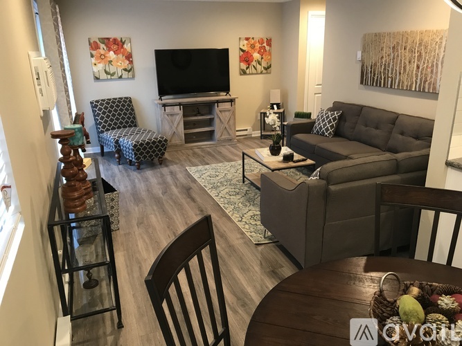 A living room with a grey couch, a black and white chair, a wooden table, and a television.