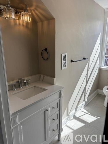 A bathroom with a sink, toilet, and a window.
