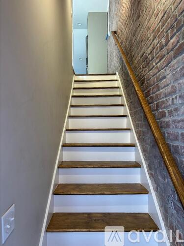 A staircase with wooden steps and a brick wall on one side.