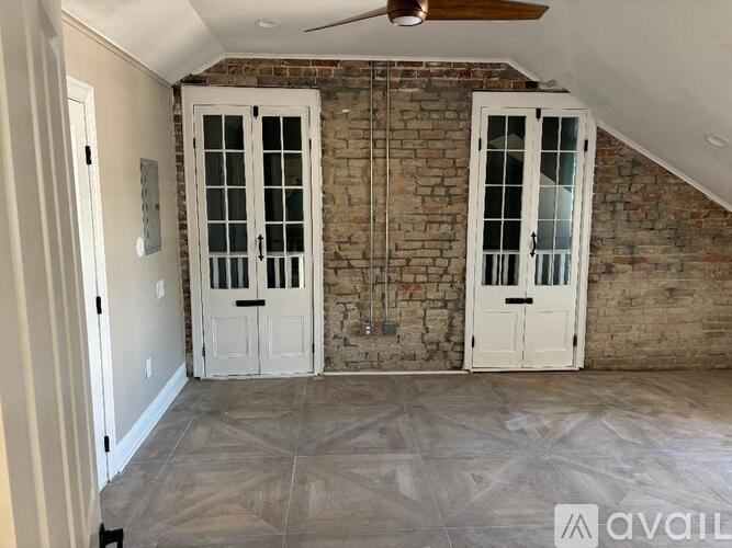 A room with a brick wall and a ceiling fan.