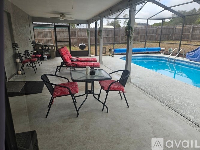 A patio with a table and chairs overlooking a pool.