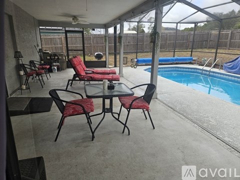 A patio with a table and chairs overlooking a pool.