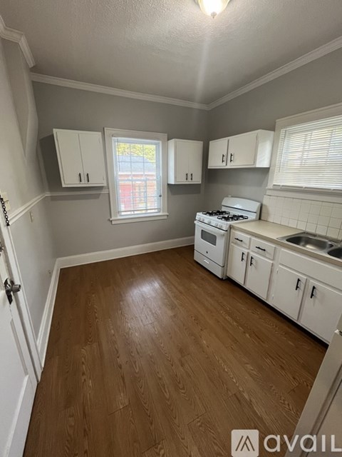 A kitchen with white cabinets and a wooden floor.