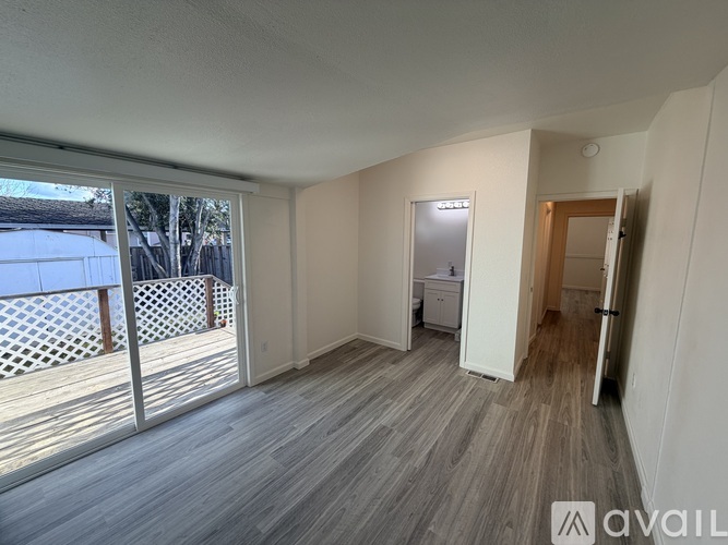 A room with wooden flooring and a white fridge in the corner.