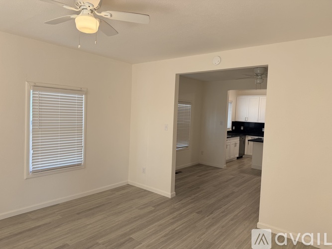 A room with a ceiling fan and a window with blinds.